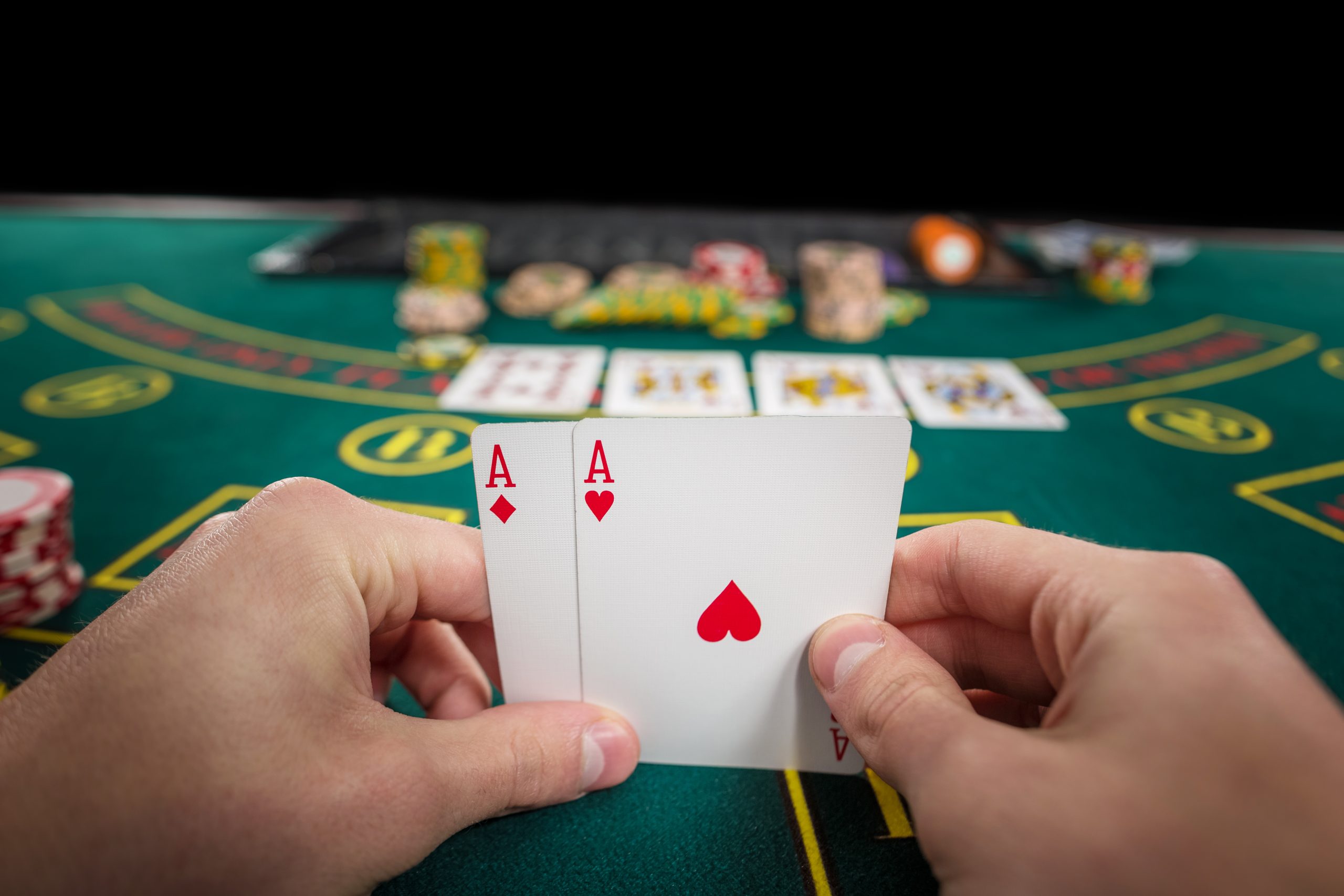 male poker player holding two cards aces scaled Almanbahis